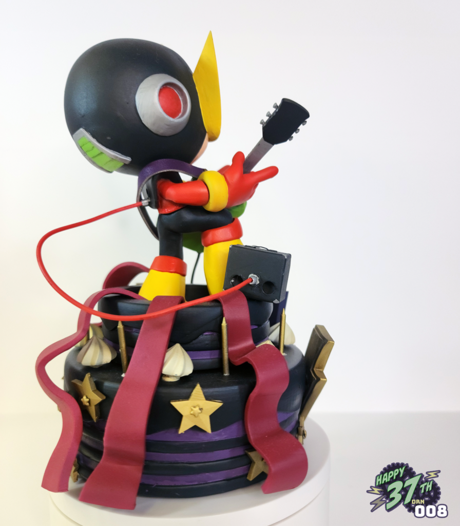 Back view of fan figure depicting Elecman standing on a purple and black cake while playing guitar